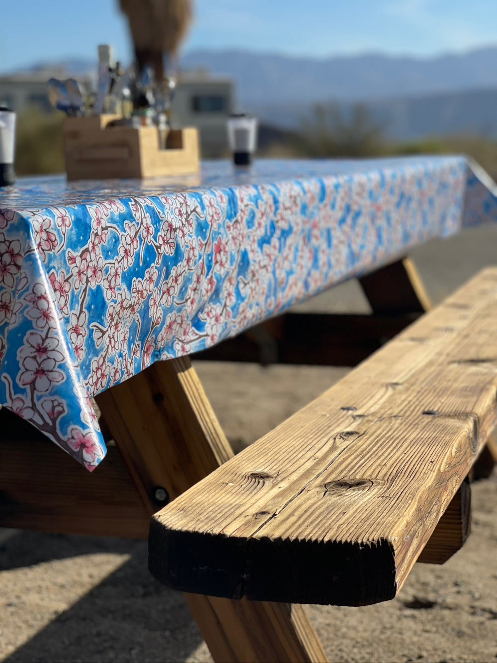 blue, red and white cherry blossom pattern outdoor tablecloth on a wooden picnic bench in the outdoors