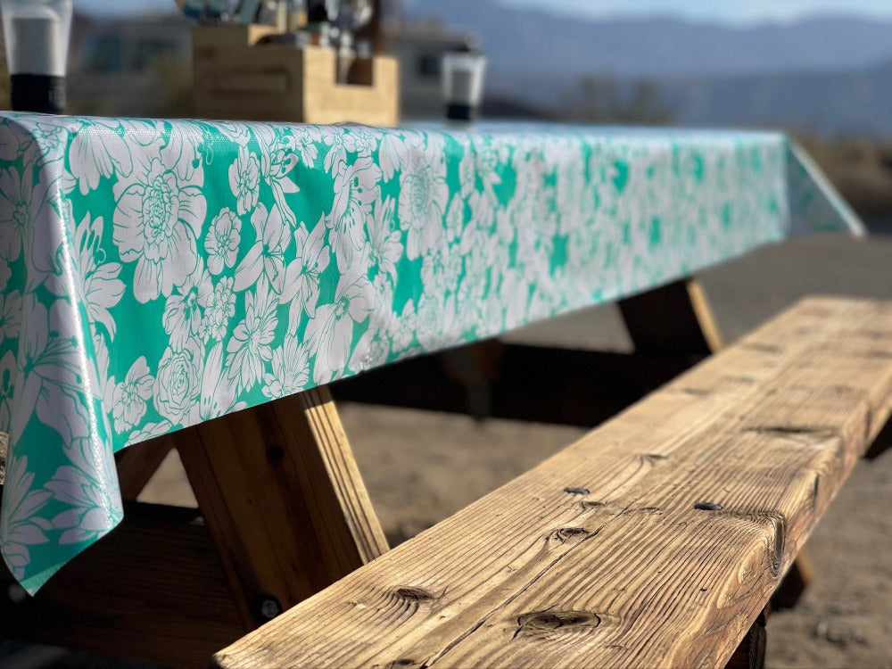 blueish green floral pattern waterproof tablecloth on wooden picnic bench