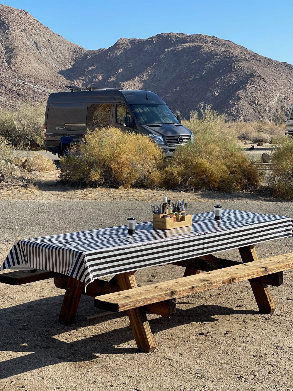 a picnic table at a desert camping site with a black and white striped outdoor tablecloth