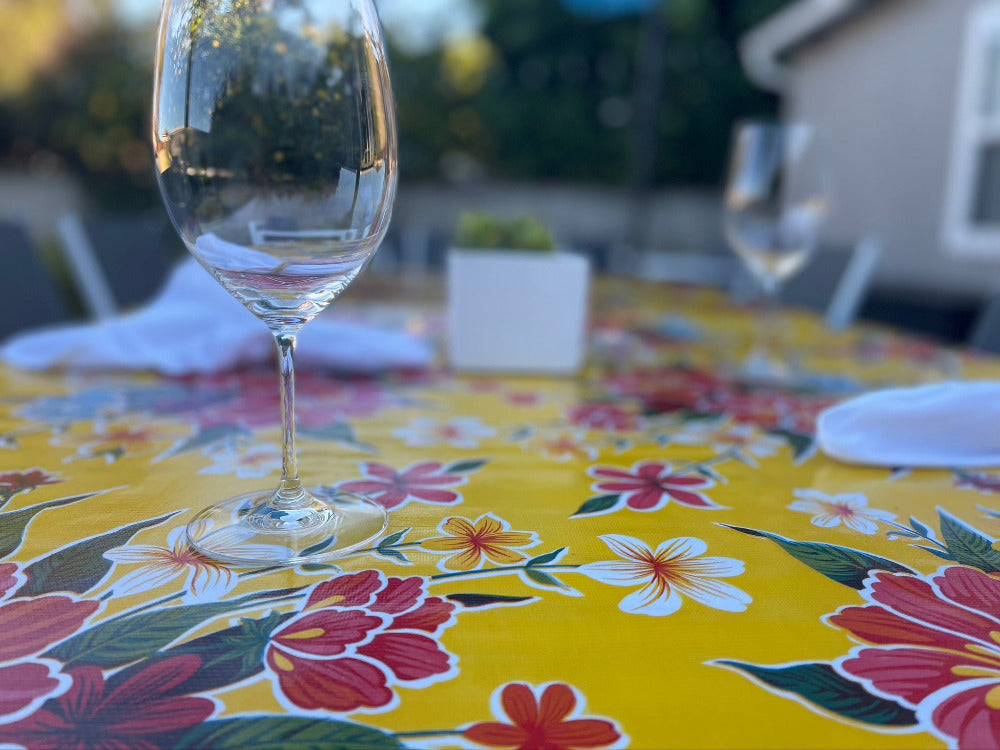 Yellow hibiscus flower pattern on outdoor tablecloth with empty wine glass