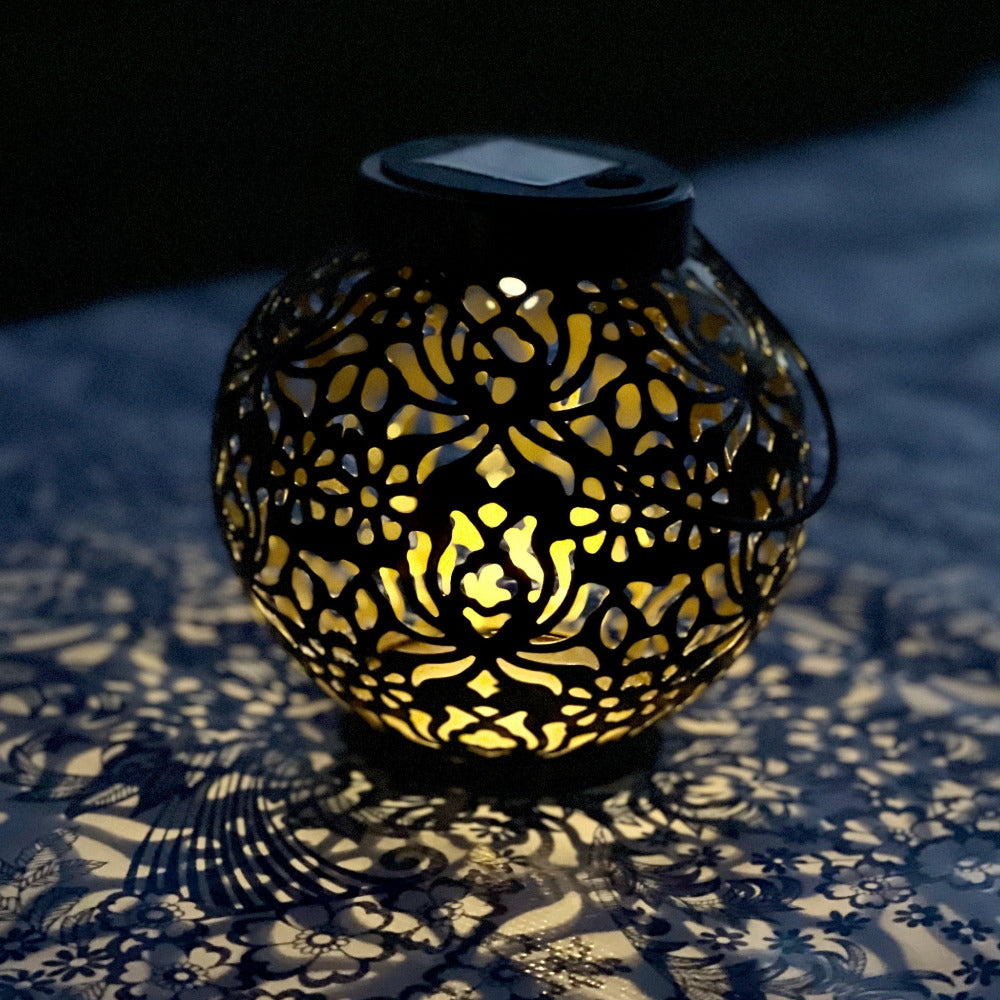 Round Hanging Solar Lantern, black, lit up at night sitting on a table